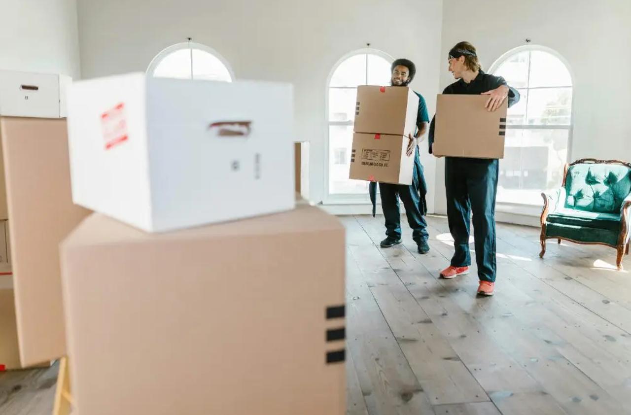 Movers carrying boxes through an empty commercial space