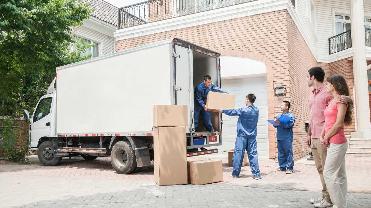 Moving crew unloading boxes from a truck at a house